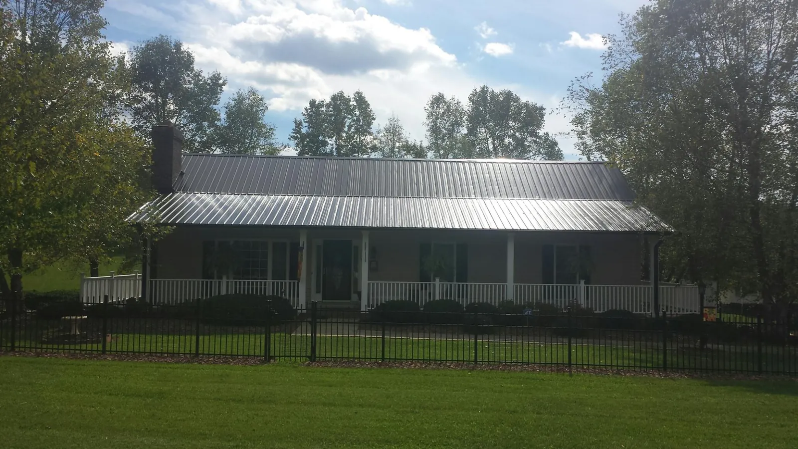 Gray metal roof on a brick ranch with a full width front porch — Gutter Guard Installation work by our crew in Dickerson