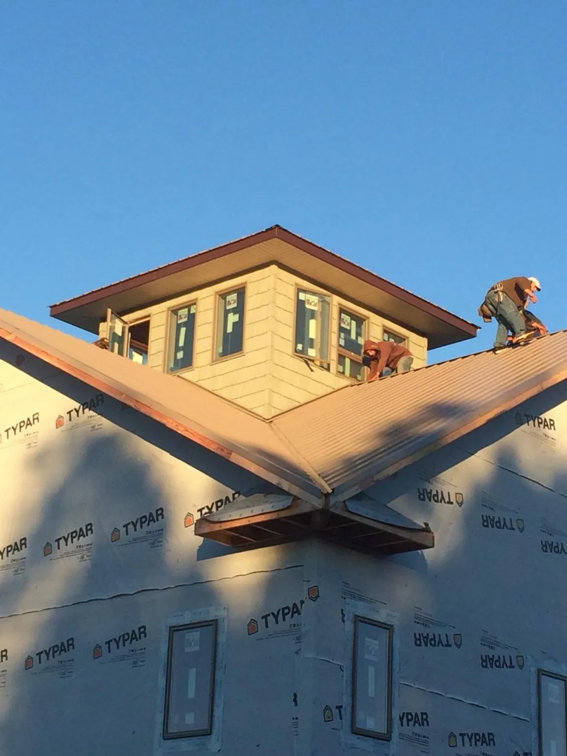 Roofers working around a rooftop cupola on a new metal roof at sunset — Roof Waterproofing in Dickerson by Roofing Brothers